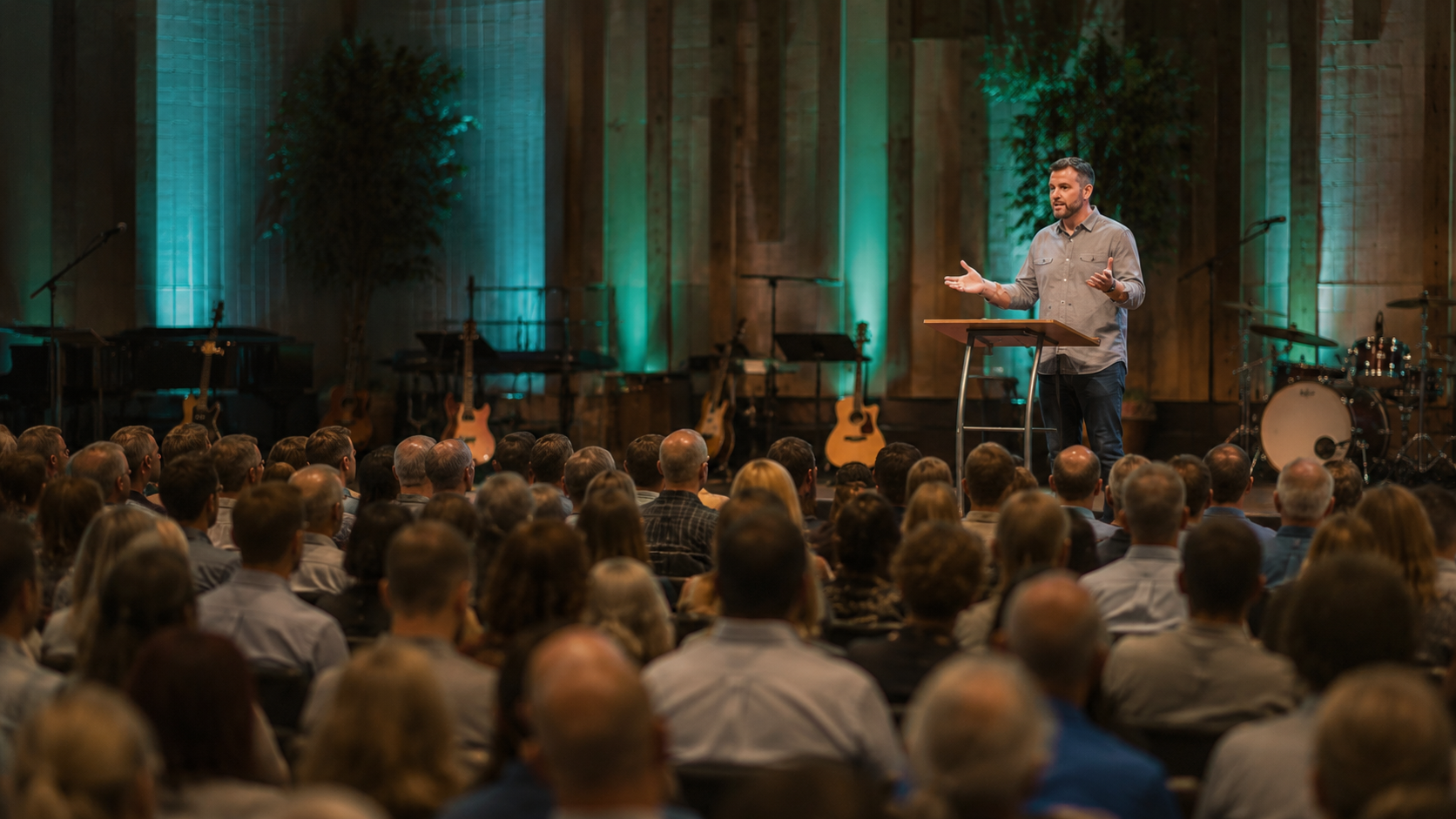 A speaker on stage during a church service with an audience listening